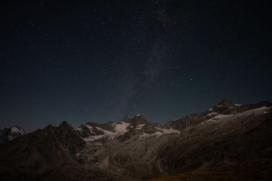 A star-filled night sky above a mountain landscape